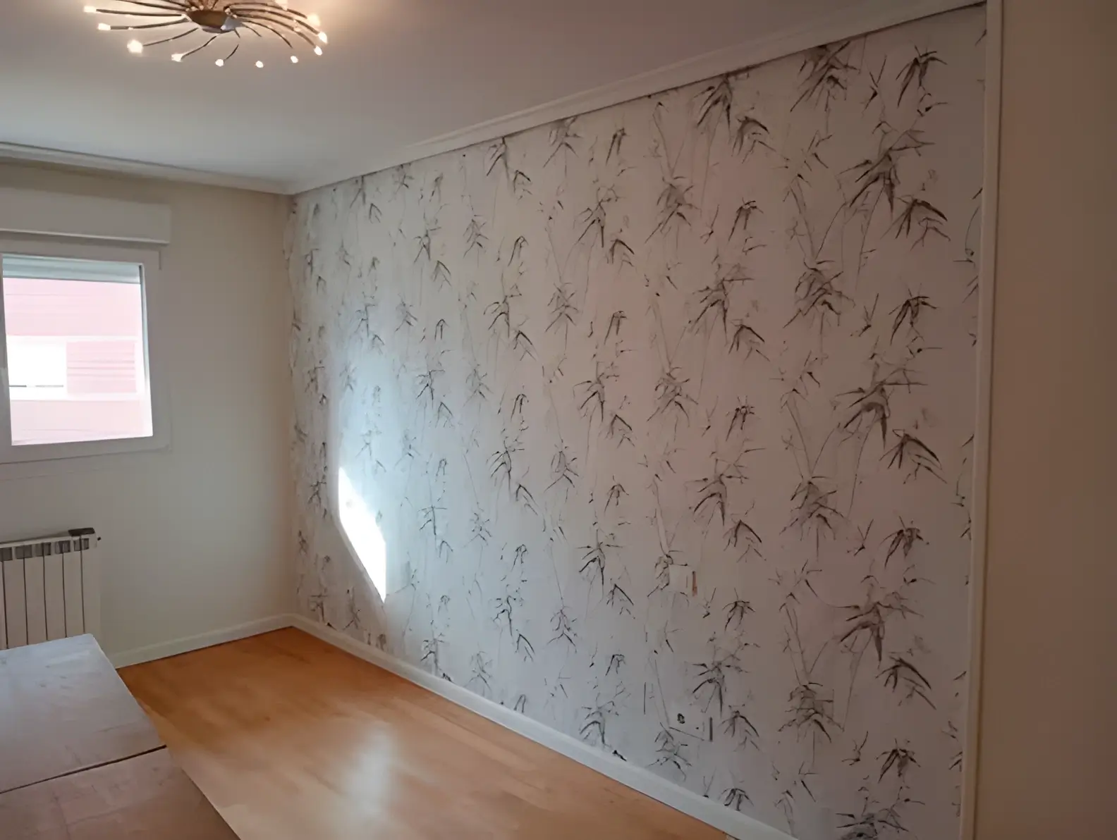 Los Pintores Sabadell colocando papel pintado en pared de acento de habitación luminosa