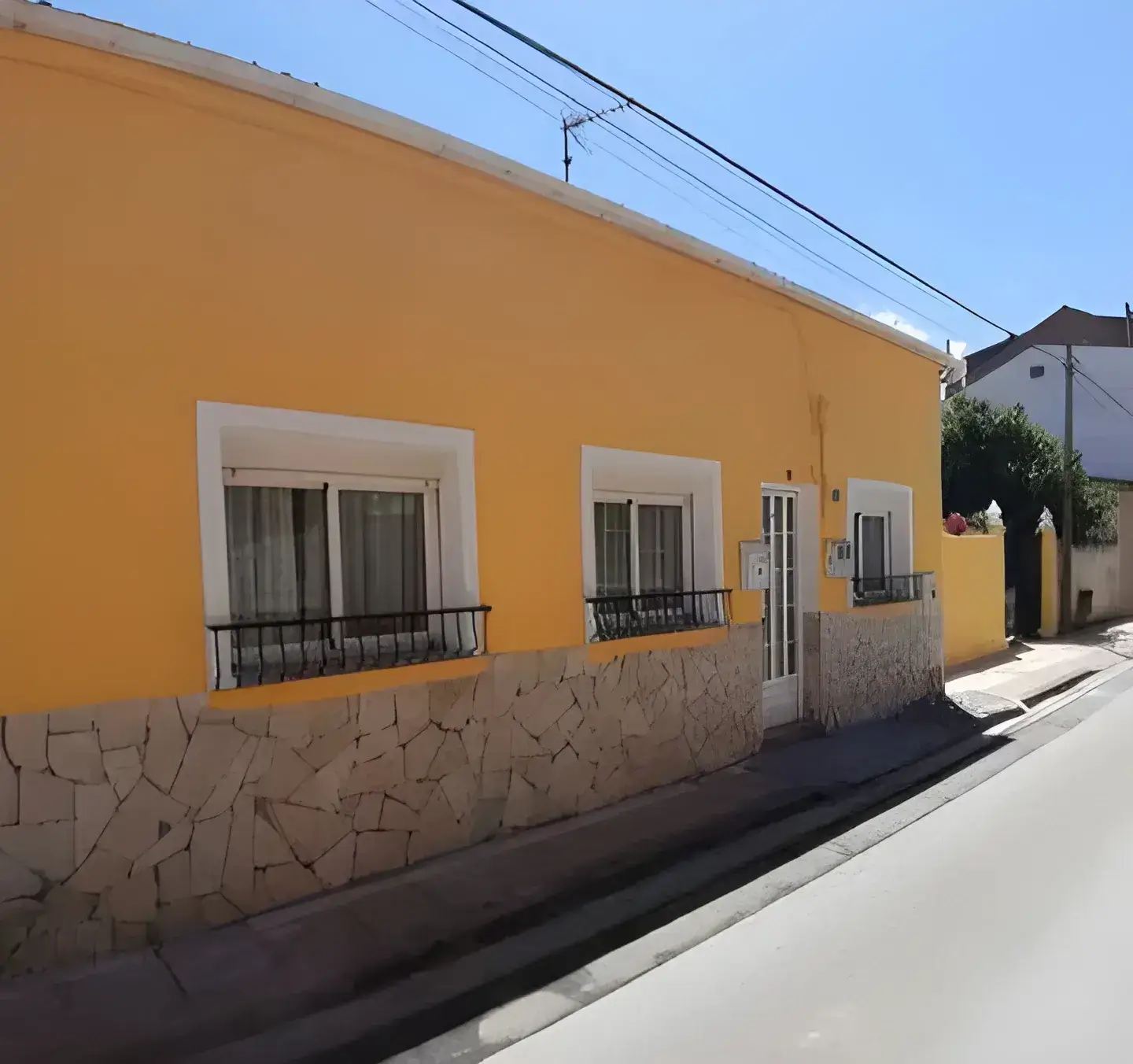 Los Pintores Sabadell Fachada de casa tradicional pintada en color amarillo con zócalo de piedra